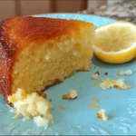 Porción de bizcocho de yogur de limón esponjoso en plato azul con rodaja de limón