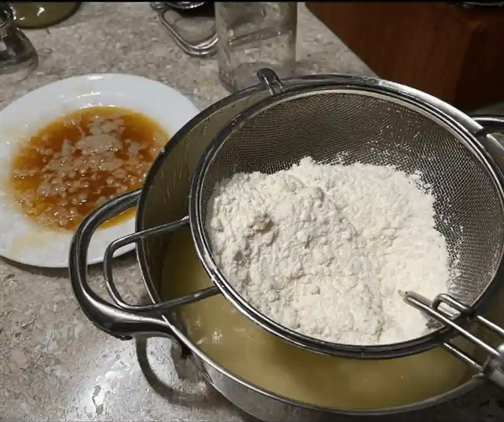 Harina tamizada sobre mezcla líquida para bizcocho de yogur de limón en un bol